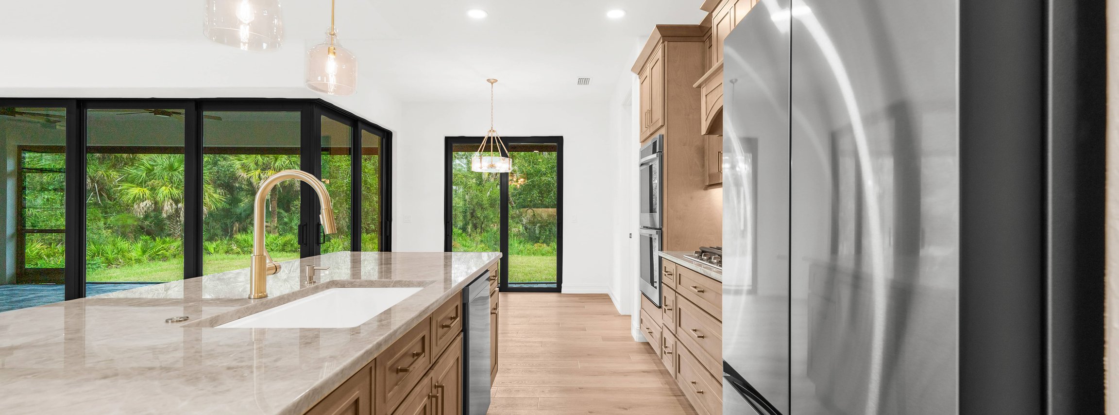 Spacious kitchen with wood cabinets, marble island, pendant lights.