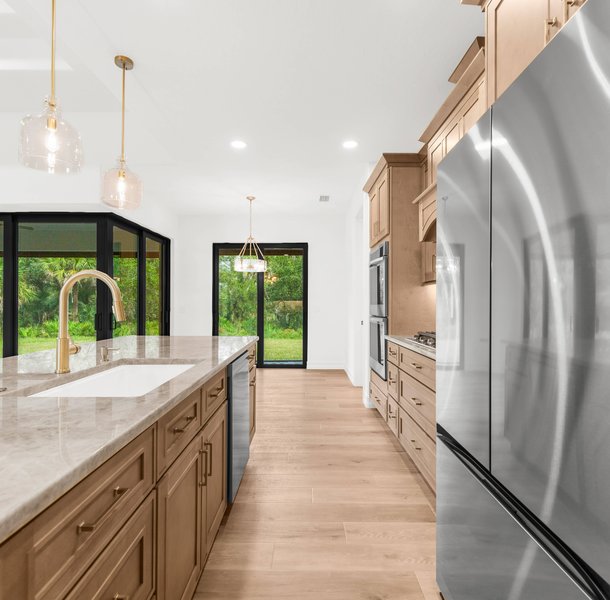 Spacious kitchen with wood cabinets, marble island, pendant lights.